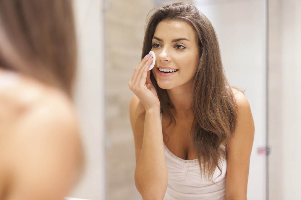 beautiful brunette woman removing makeup